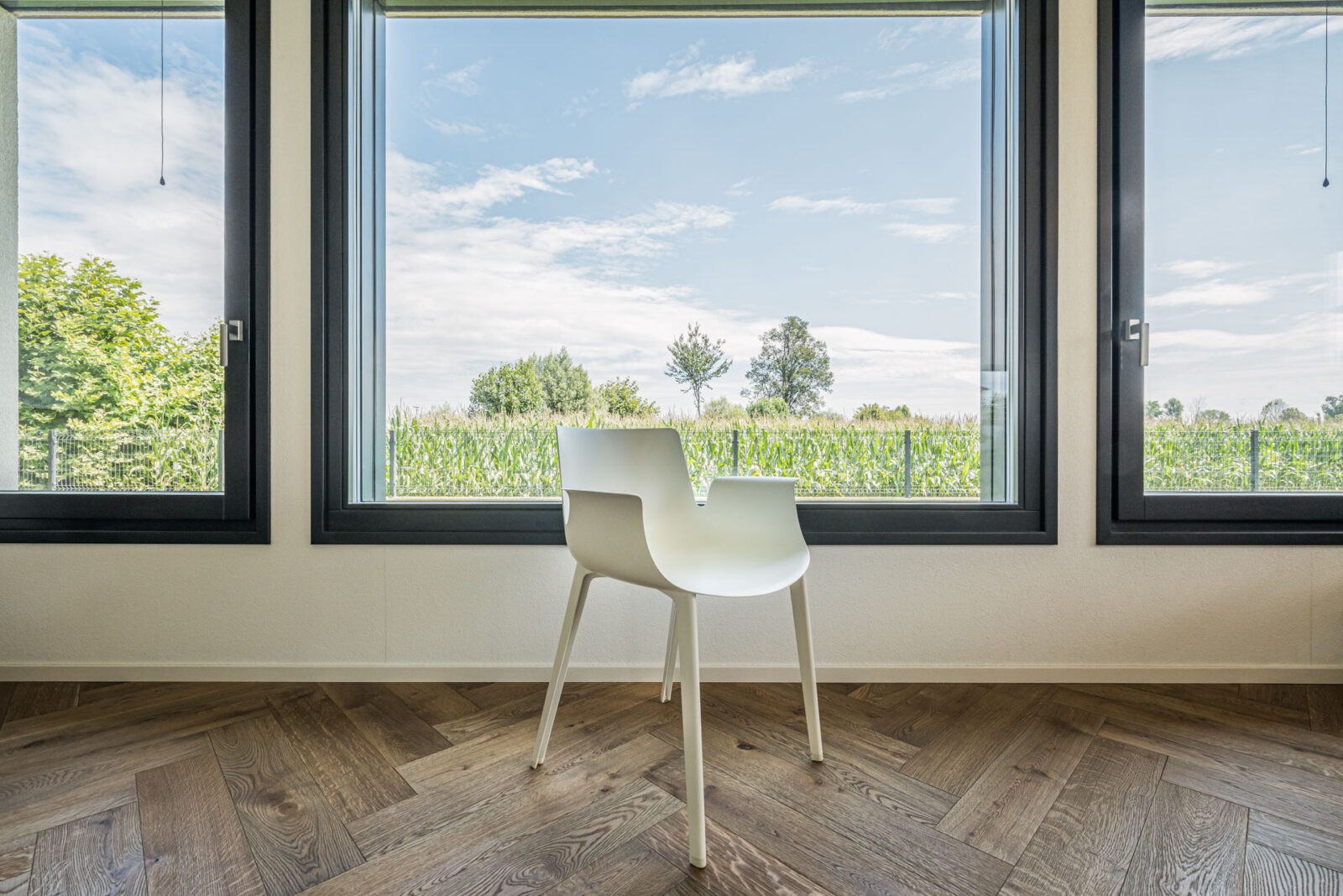 sedia bianca moderna all'interno di una stanza con grandi vetrate e parquet - dettaglio di foto di architettura