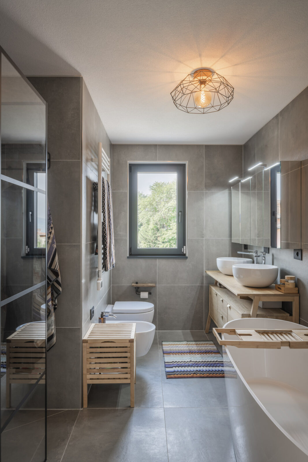 bagnocon piastrelle dai colori caldi e vasca ovale in corian
