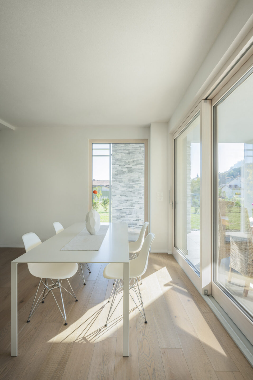 particolare di sala da pranzo moderna inondata dalla luce del sole proveniente dalle grandi vetrate che la circondano