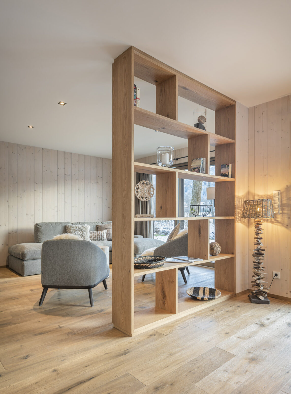 salotto in legno con mobile a scaffale che funge da divisore tra con il soggiorno
